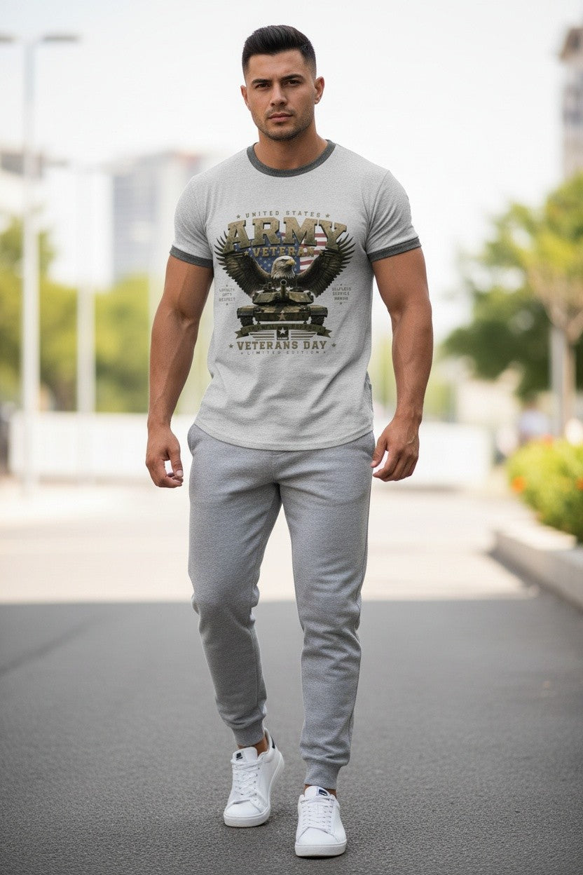 A man walking outdoors wearing a light gray ringer t-shirt with a dark graphic print and matching gray sweatpants, paired with white sneakers.