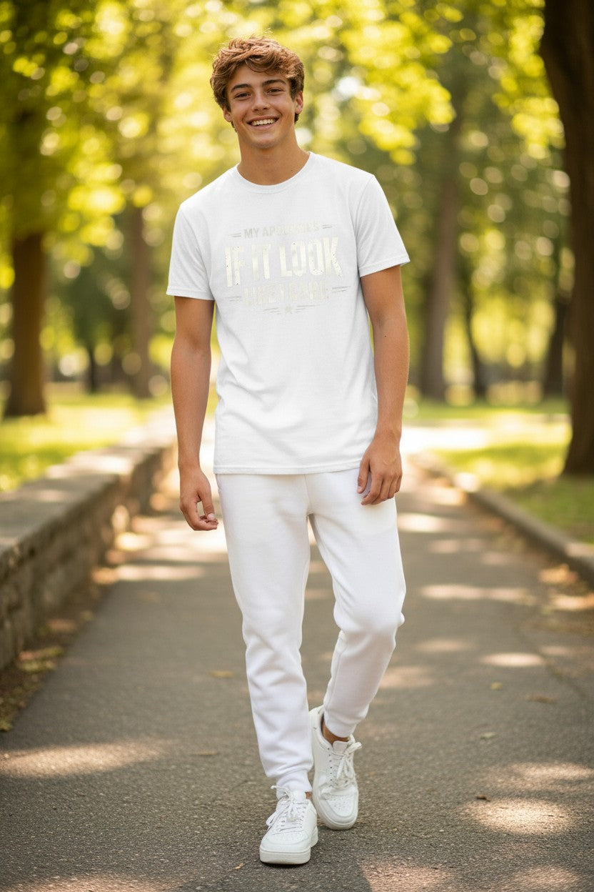 A young man walking on a sunlit park path wearing a white graphic t-shirt, white sweatpants, and white sneakers.