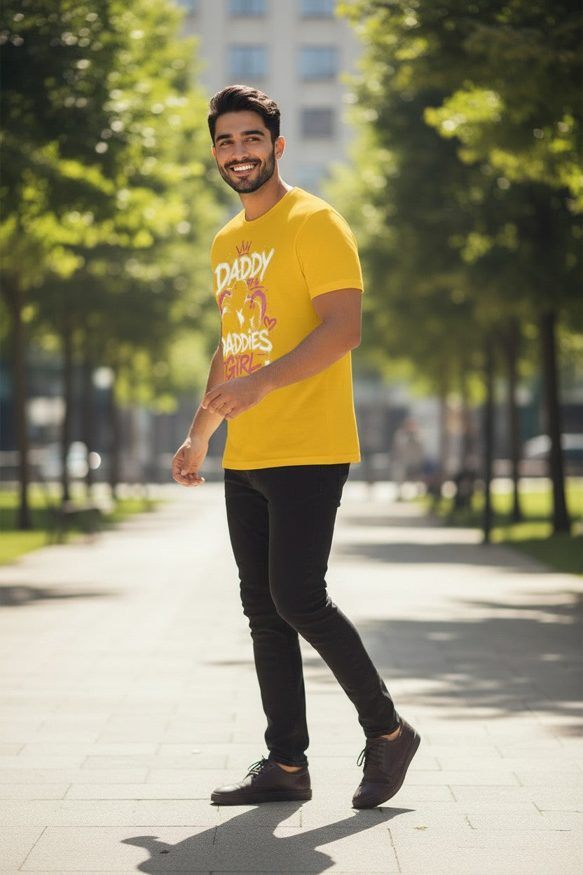 Man wearing a yellow t-shirt with text and graphics, standing on a sunny day in an urban park.
