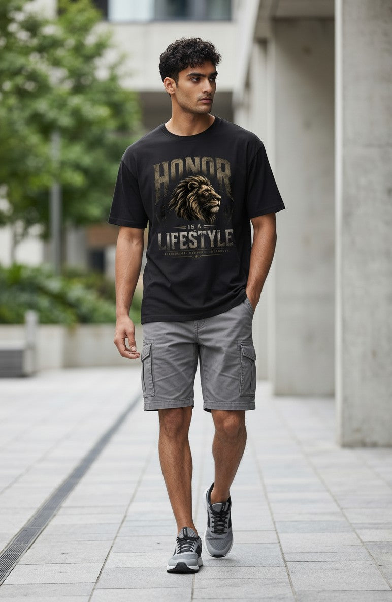 Man wearing a black t-shirt with a graphic design and text, standing on a sidewalk.