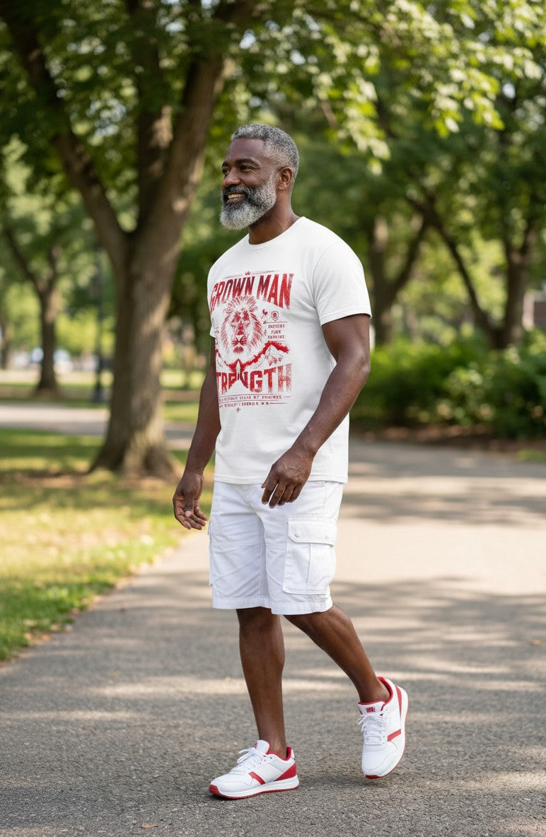 Man walking outdoors wearing a white t-shirt with red graphics and text, white shorts, and red and white sneakers.