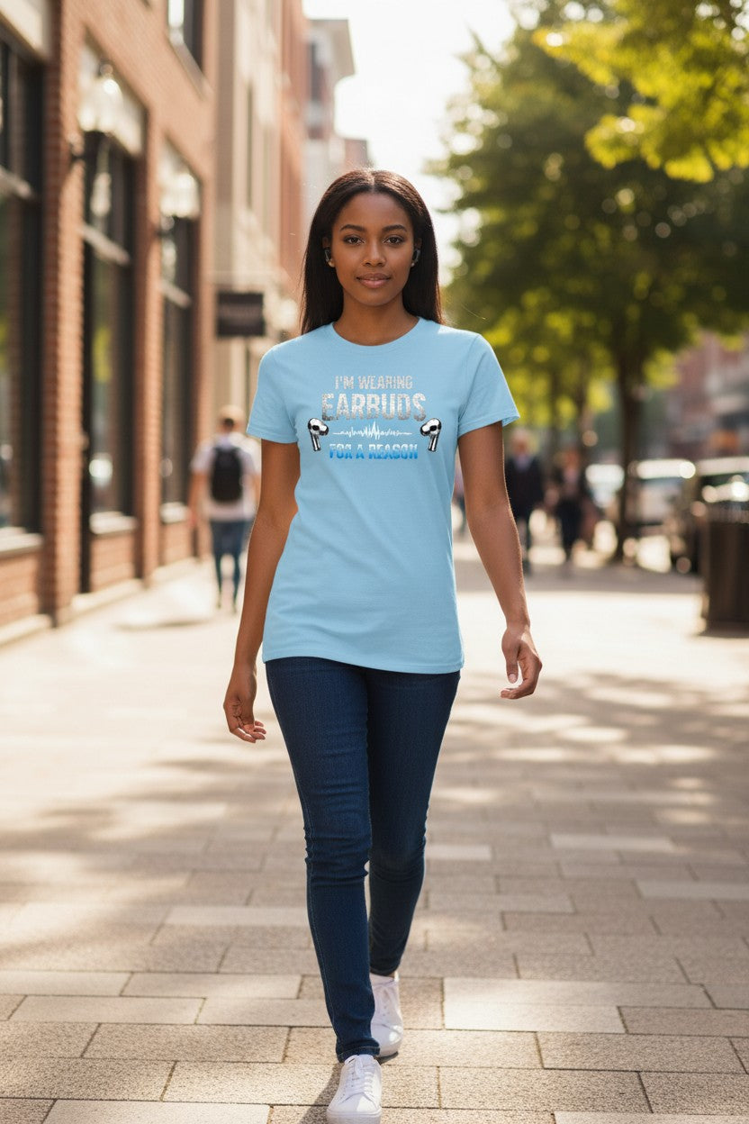 Woman walking on a sidewalk wearing a light blue t-shirt with text and graphics.