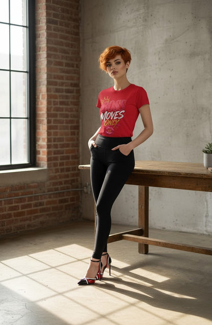 Woman in a red t-shirt and black pants standing in a sunlit room with brick walls and a wooden table.