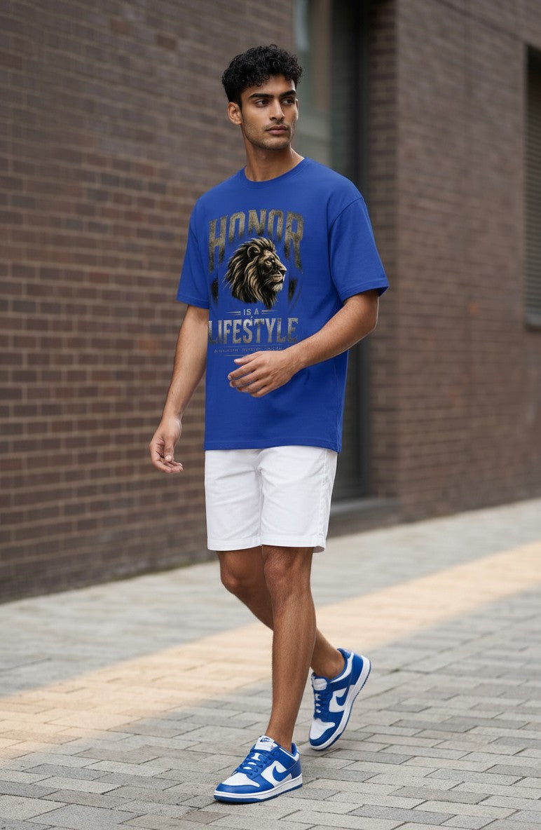 Man wearing a blue t-shirt with a lion graphic and text, white shorts, and blue sneakers on a sidewalk.