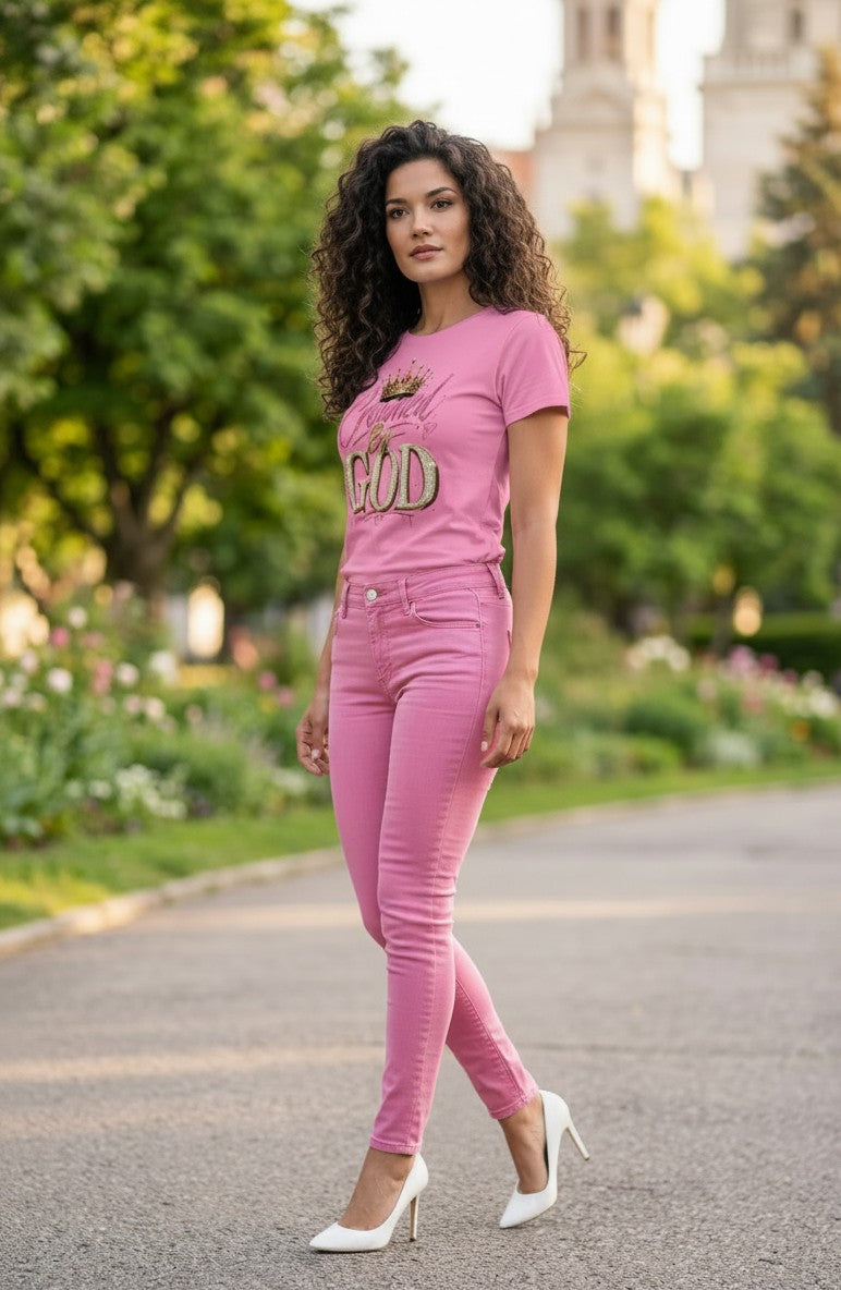Woman wearing a pink t-shirt and pants standing on a path with greenery in the background