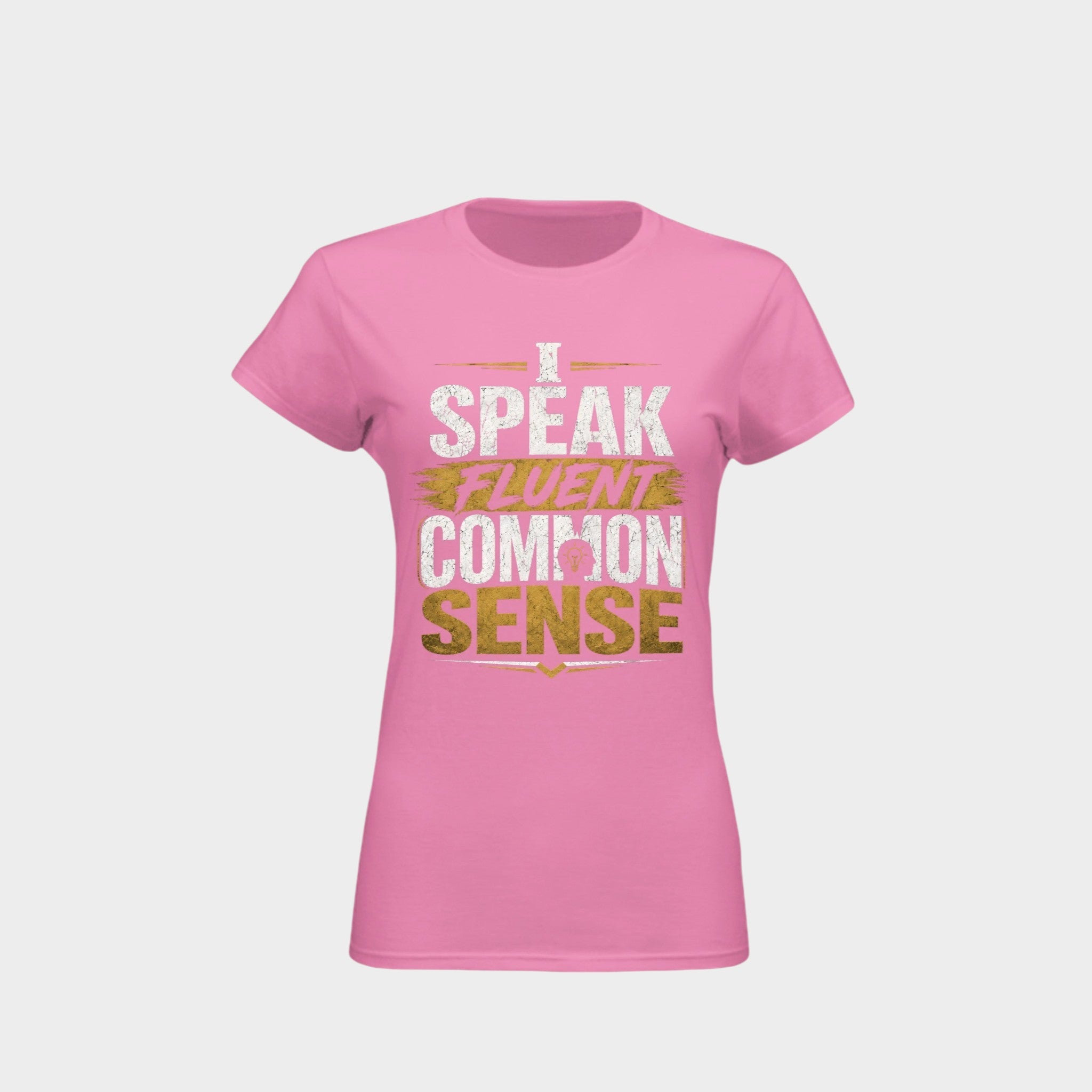 A pink short-sleeve crewneck t-shirt with a graphic text print reading 'I SPEAK FLUENT COMMON SENSE' in distressed white and gold lettering, shown on a light gray background.