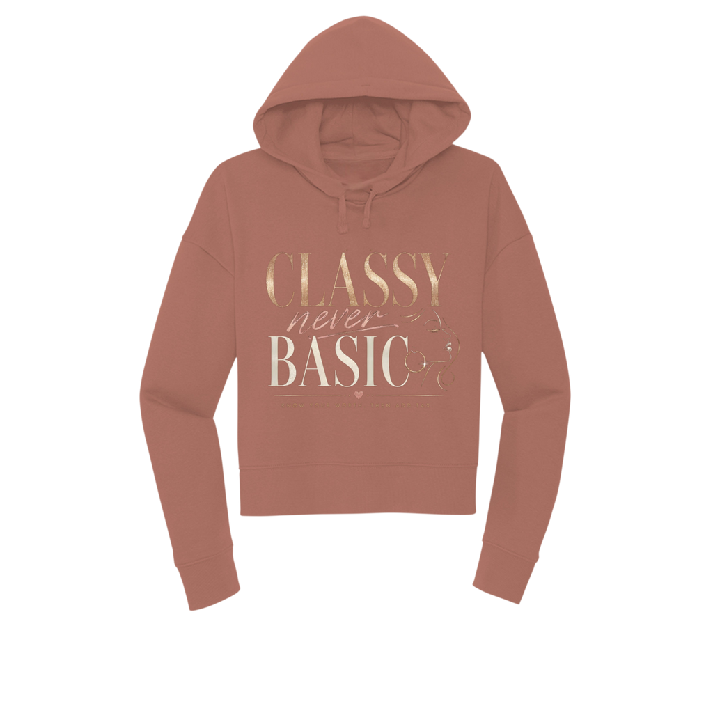 A dusty rose cropped hoodie with a metallic gold graphic print on the front reading 'CLASSY never BASIC'. The hoodie is shown against a plain white background.