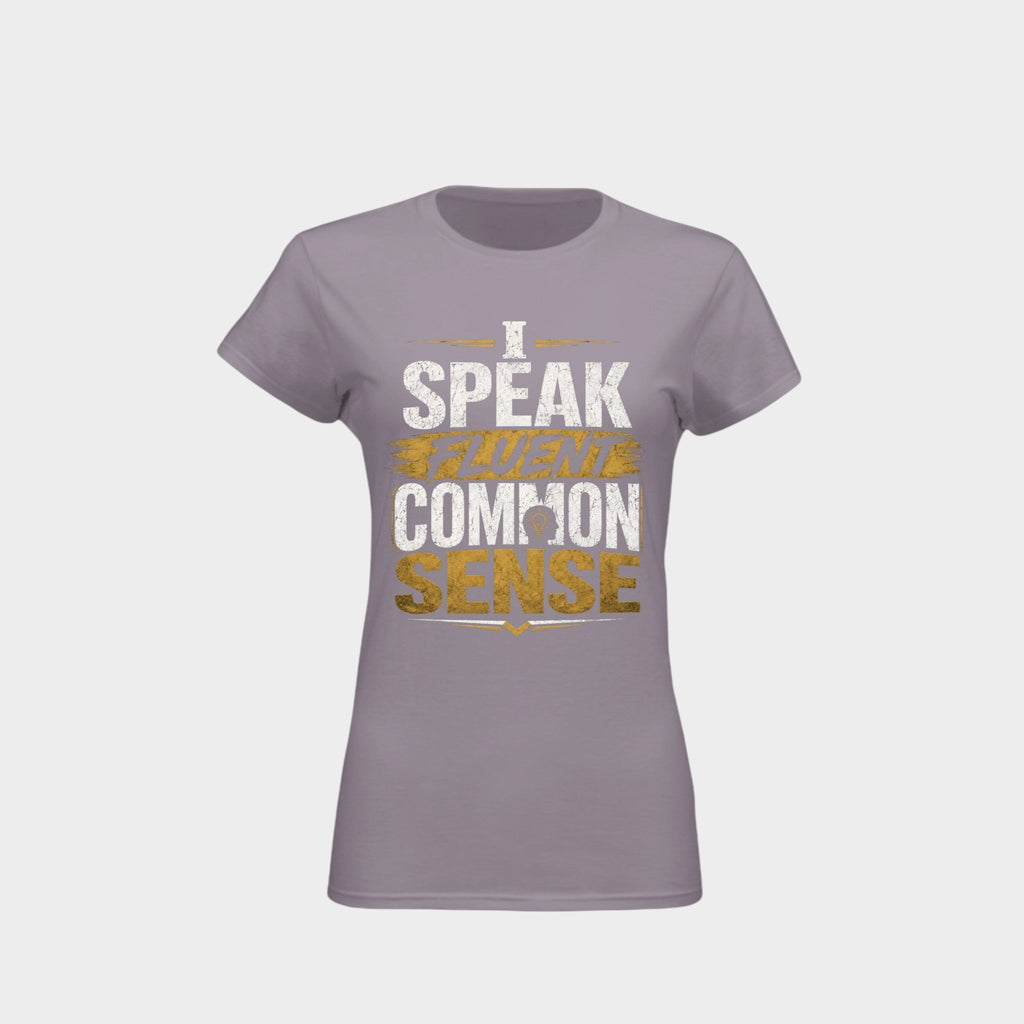 A women's short-sleeve crewneck t-shirt in a muted lavender-gray color, featuring a distressed graphic print on the front that reads 'I SPEAK TRUTH IN COMMON SENSE' in white and gold lettering, set against a light gray background.