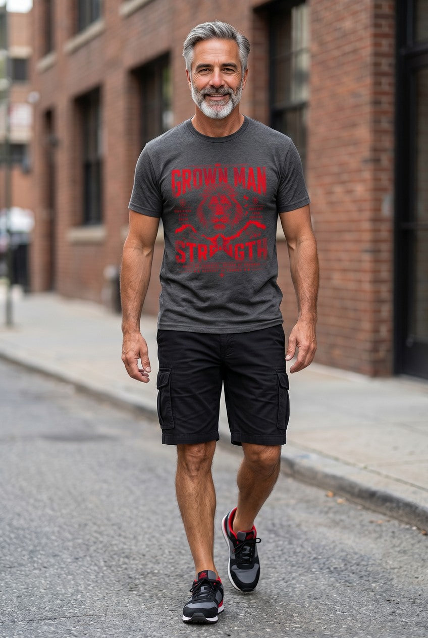 Man walking on a street wearing a gray t-shirt with red graphics and black shorts.