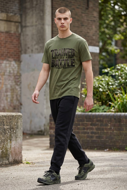 Man wearing a green t-shirt with text, standing outdoors near a brick wall.