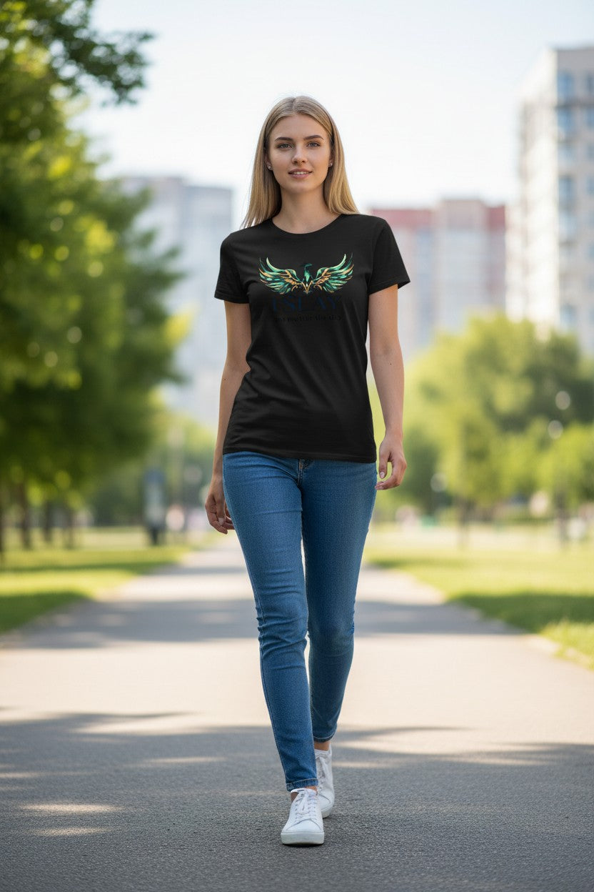 Woman wearing a black t-shirt with a green design and blue jeans walking on a path with trees and buildings in the background.