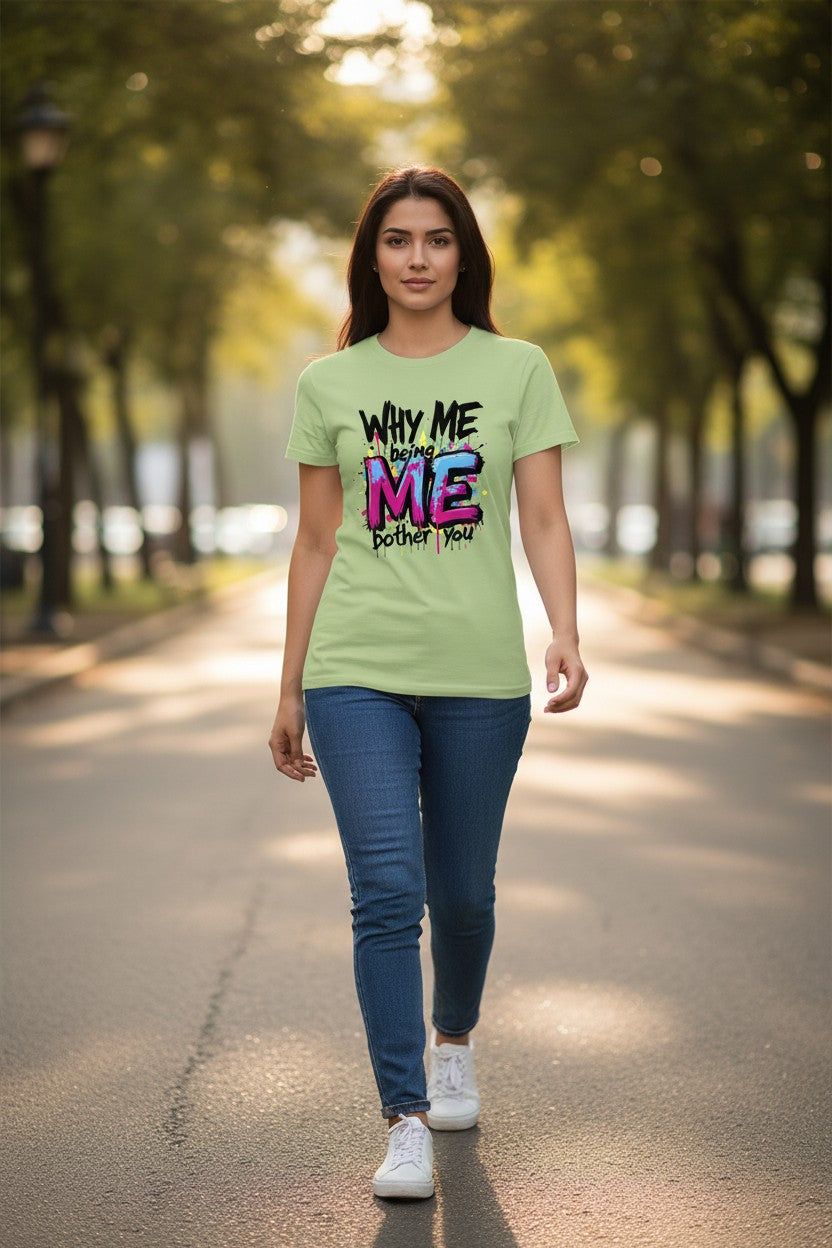 Woman wearing a light green t-shirt with colorful text walking on a tree-lined path.