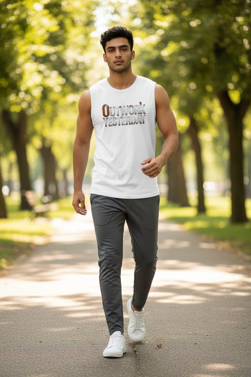 Man walking in a park wearing a white sleeveless shirt with text and dark pants.