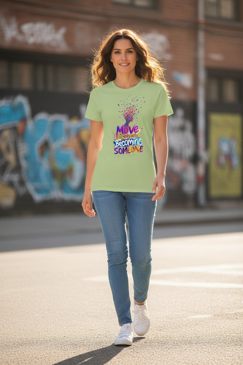 Woman wearing a light green t-shirt with colorful text and graphics, standing on a street with graffiti in the background.