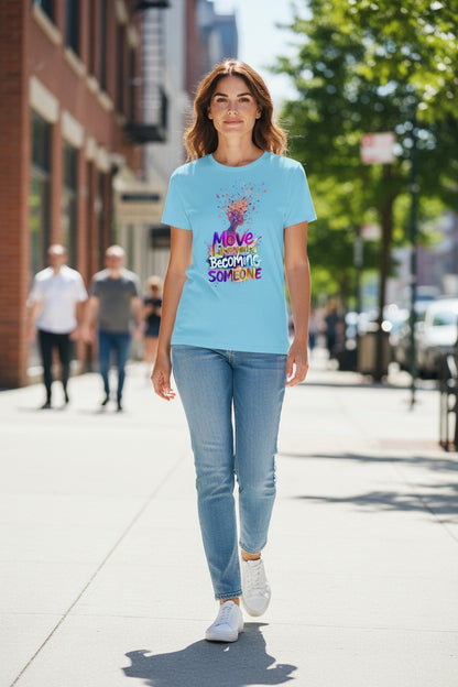 Woman walking on a city street wearing a light blue t-shirt with colorful text design.