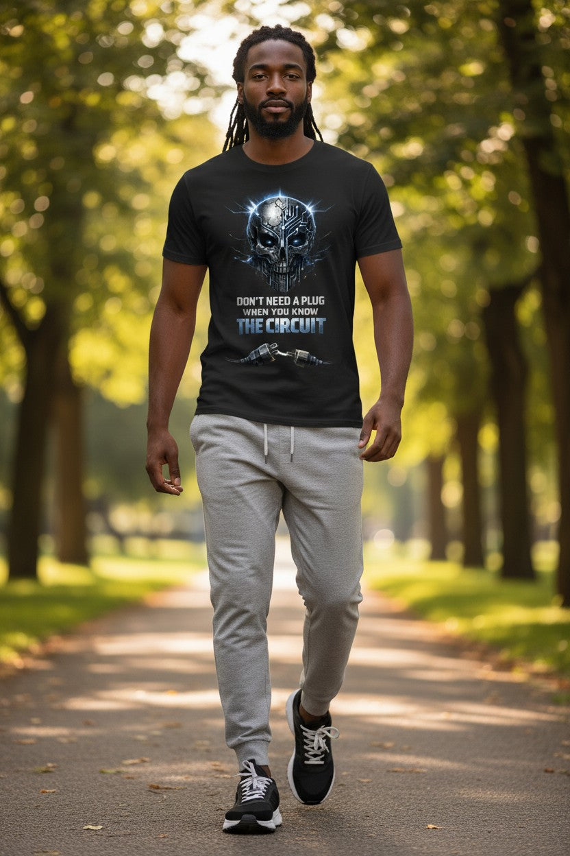 Man walking on a path in a park wearing a black t-shirt with graphic design and text.