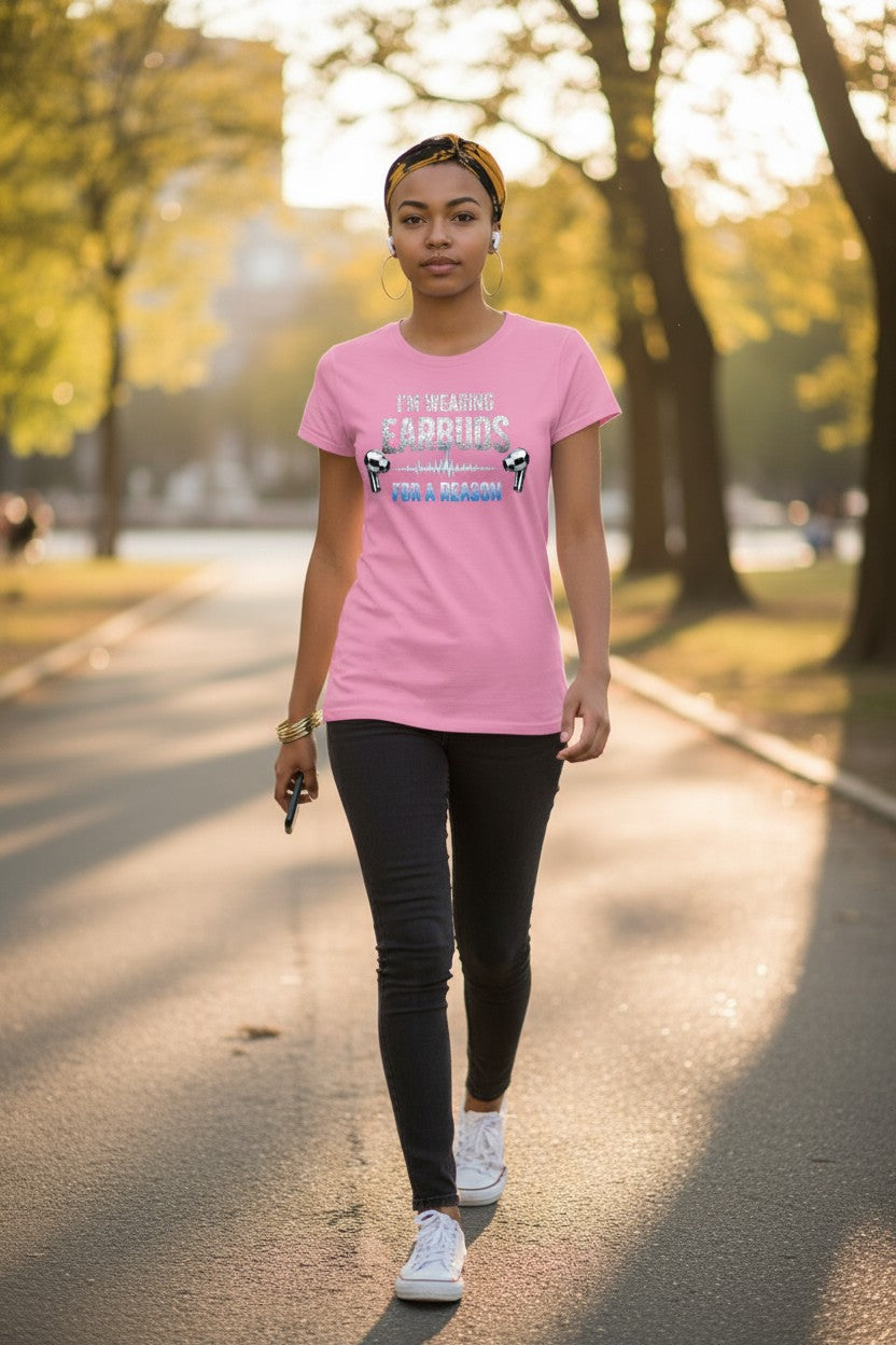 Woman walking on a path in a park wearing a pink t-shirt with text and graphics.