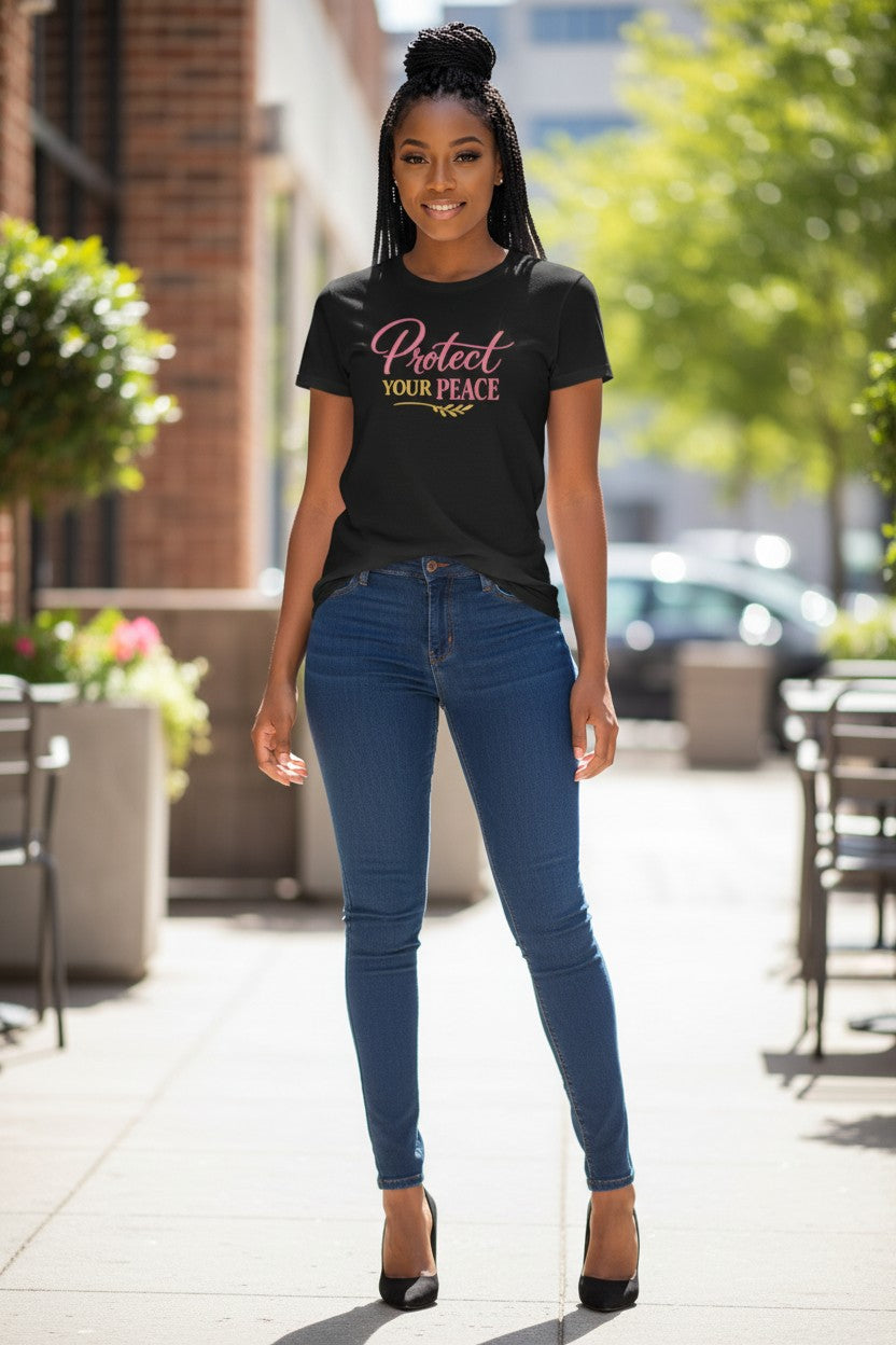 Woman wearing a black t-shirt with 'Protect Your Peace' text and blue jeans standing outdoors.