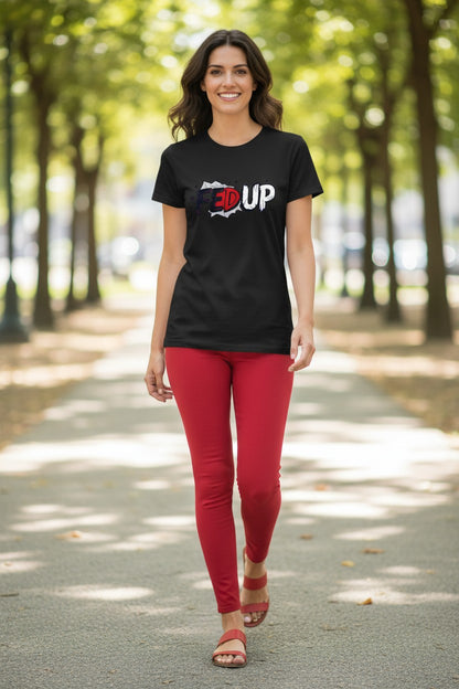 Woman wearing a black t-shirt with '3UP' logo and red pants walking on a tree-lined path.