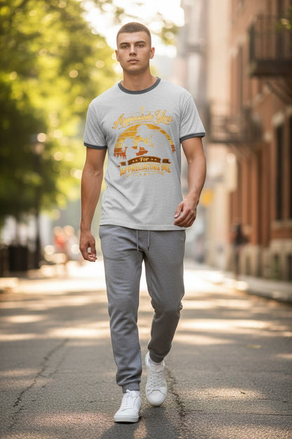 Man walking on a street wearing a gray t-shirt with a graphic design and gray pants.