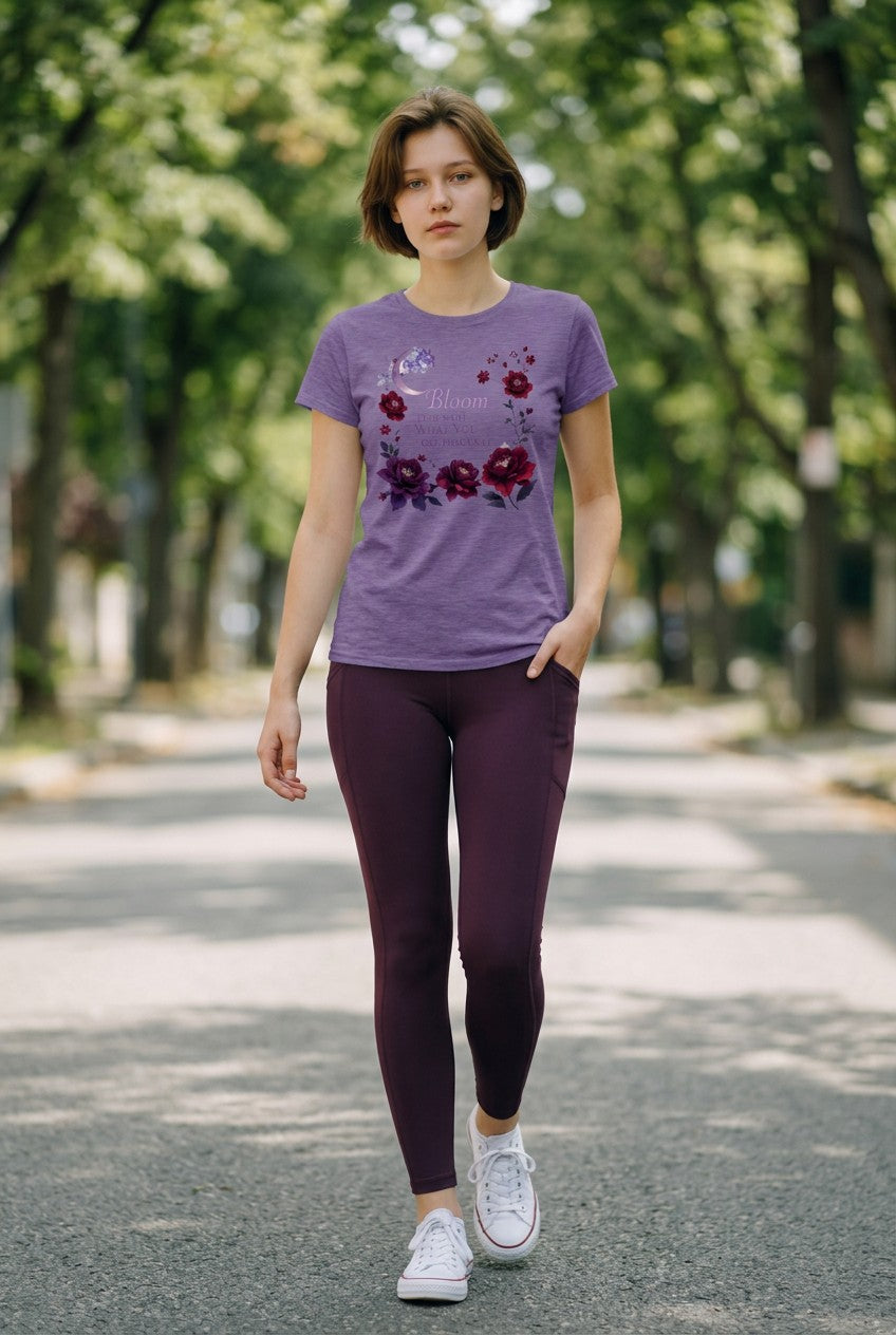 Woman wearing a purple t-shirt with floral designs and dark leggings walking on a path with trees in the background.