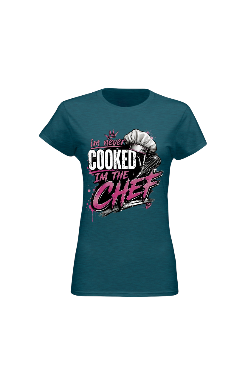 A women's short-sleeve crewneck t-shirt in teal, featuring a graphic print on the front with a chef's hat and the text 'I'm never COOKED I'M THE CHEF' in white and pink.