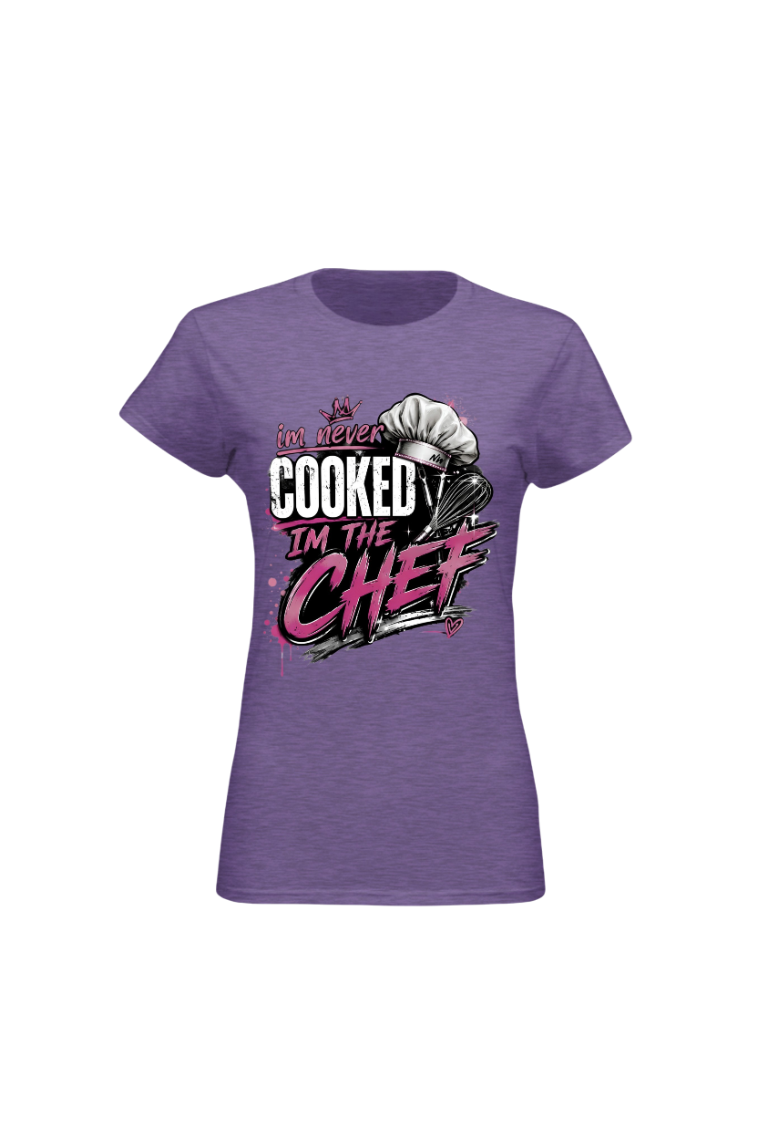 A women's short-sleeve crewneck t-shirt in heather purple, featuring a graphic print on the front with the text 'I DO NEVER COOKED I'M THE CHEF' in white and pink lettering alongside a chef's hat illustration.
