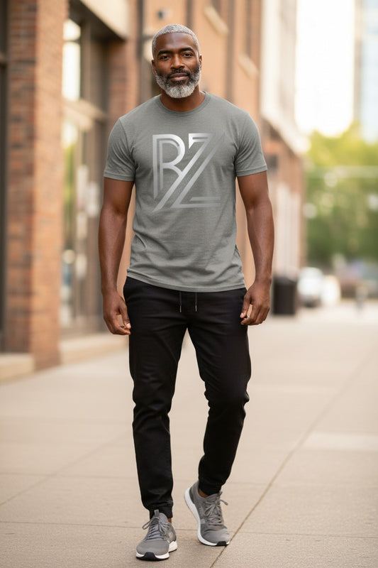 Man wearing a gray t-shirt with a logo, standing on a sidewalk.