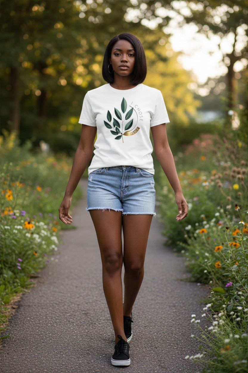 Woman walking on a path surrounded by nature wearing a white t-shirt with a leaf design.