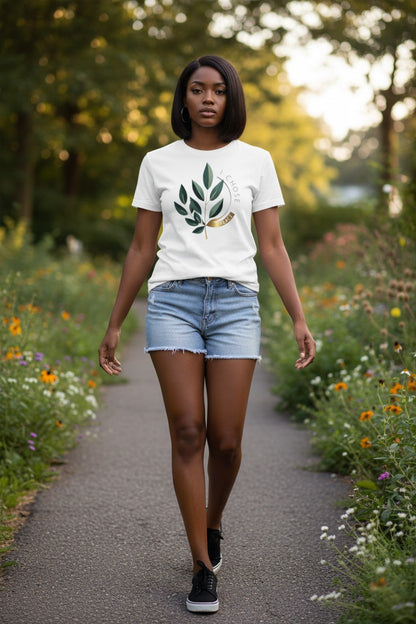 Woman walking on a path surrounded by nature wearing a white t-shirt with a leaf design.
