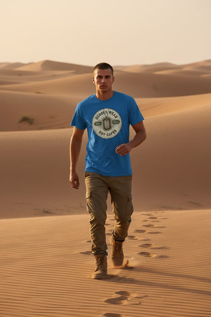 Man walking on sand dunes in a desert wearing a blue t-shirt and beige pants.