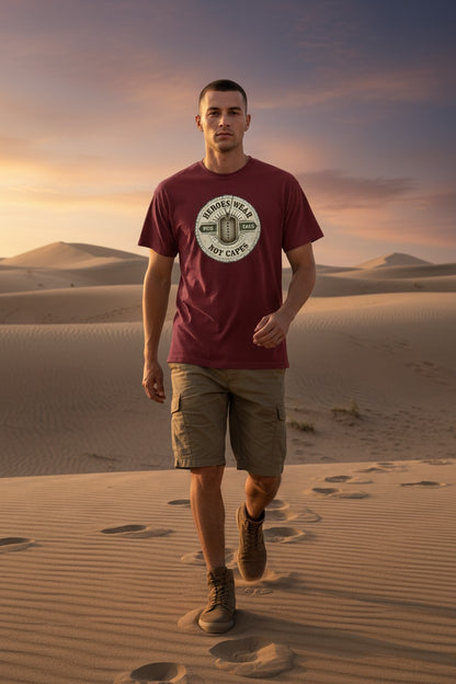 Man in a red t-shirt with a logo walking on sand dunes at sunset.