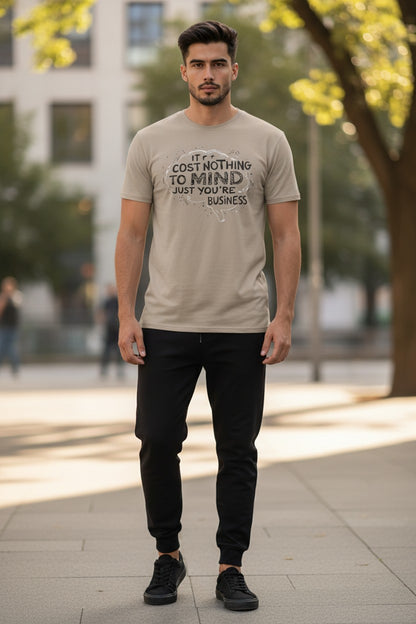 Man wearing a beige t-shirt with text and black pants standing outdoors.