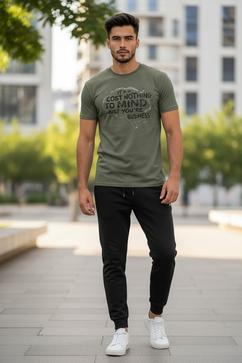 Man wearing a green t-shirt with text and black pants standing outdoors.