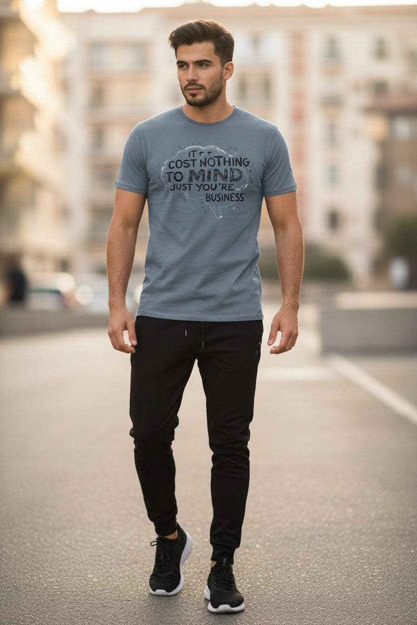 Man wearing a gray t-shirt with text and black pants on a street.