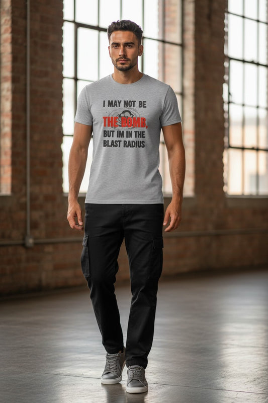 Man wearing a gray t-shirt with humorous text in an indoor setting with large windows and brick walls.