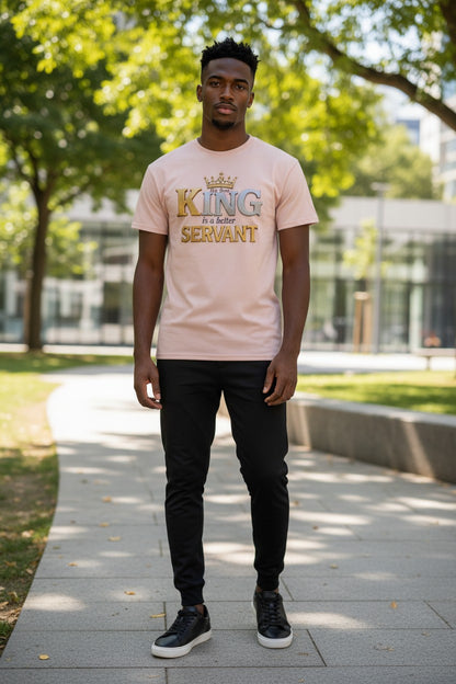Man wearing a pink t-shirt with 'King is a better servant' text standing outdoors.
