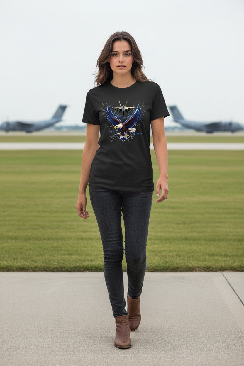 Woman wearing a black t-shirt with an eagle design on a grassy area with airplanes in the background