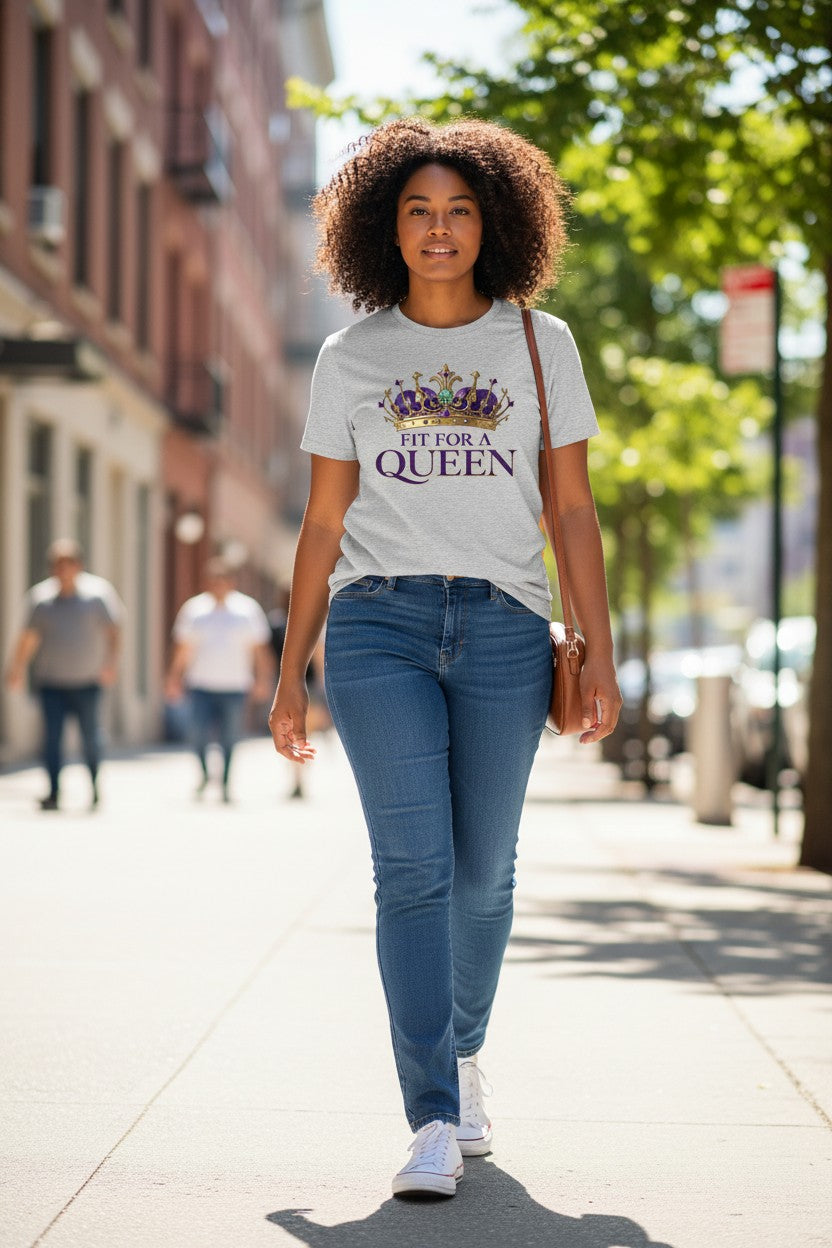 Woman walking on a sidewalk wearing a t-shirt with 'Fit for a Queen' text.