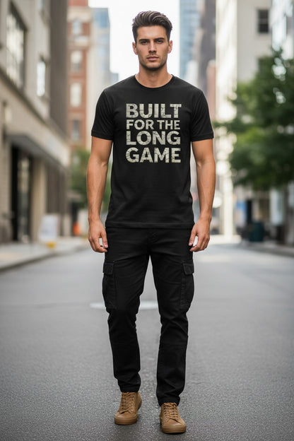 Man wearing a black t-shirt with 'BUILT FOR THE LONG GAME' text on a city street.