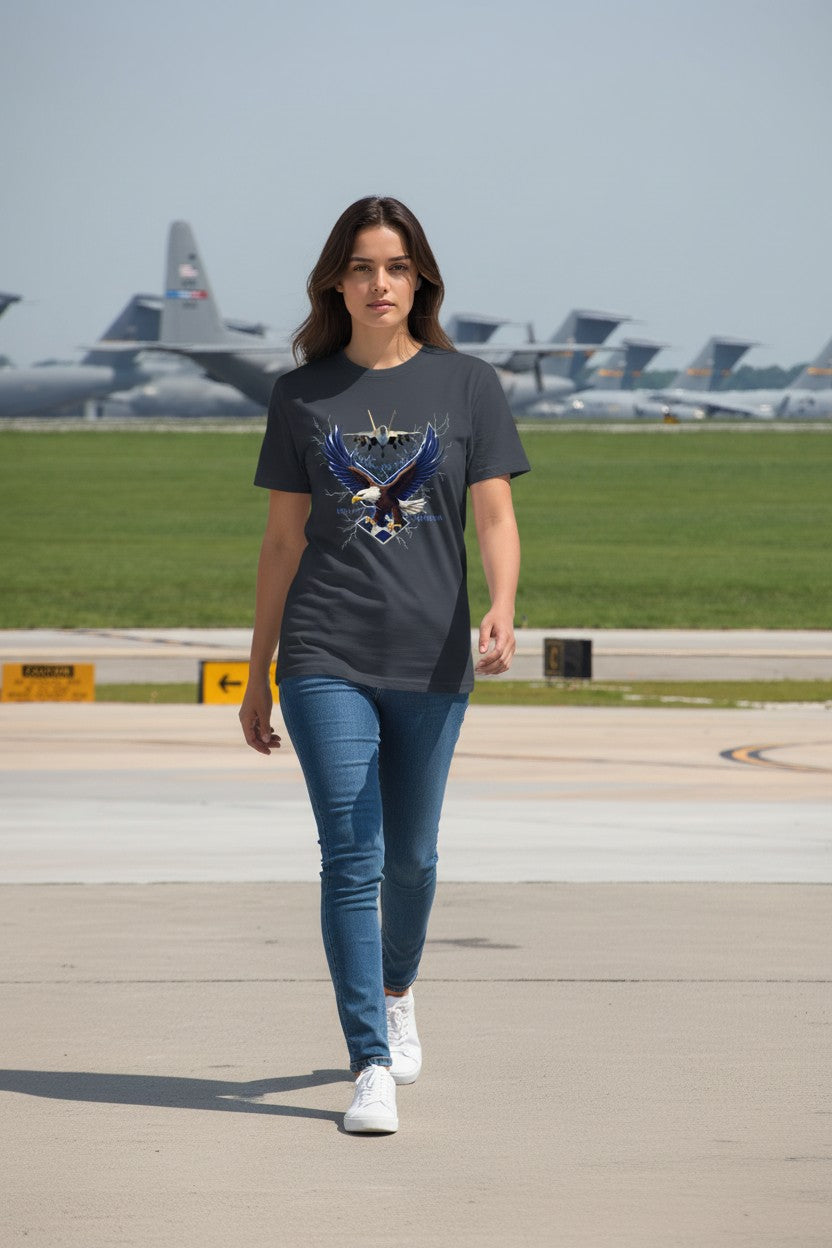 Woman walking on an airport tarmac wearing a graphic t-shirt with airplanes in the background.
