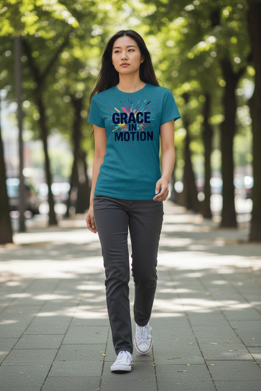 Woman wearing a teal t-shirt with 'Grace in Motion' text walking on a tree-lined street.