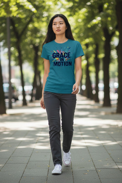 Woman wearing a teal t-shirt with 'Grace in Motion' text walking on a tree-lined street.