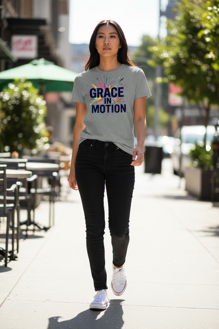 Woman walking on a sidewalk wearing a gray t-shirt with 'Grace in Motion' text.