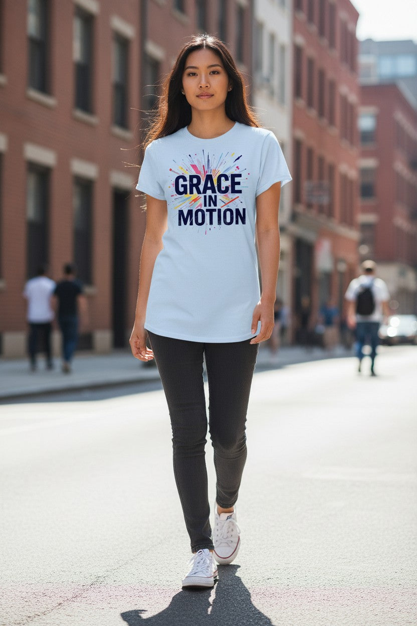Person wearing a light blue t-shirt with 'Grace in Motion' text on a city street.