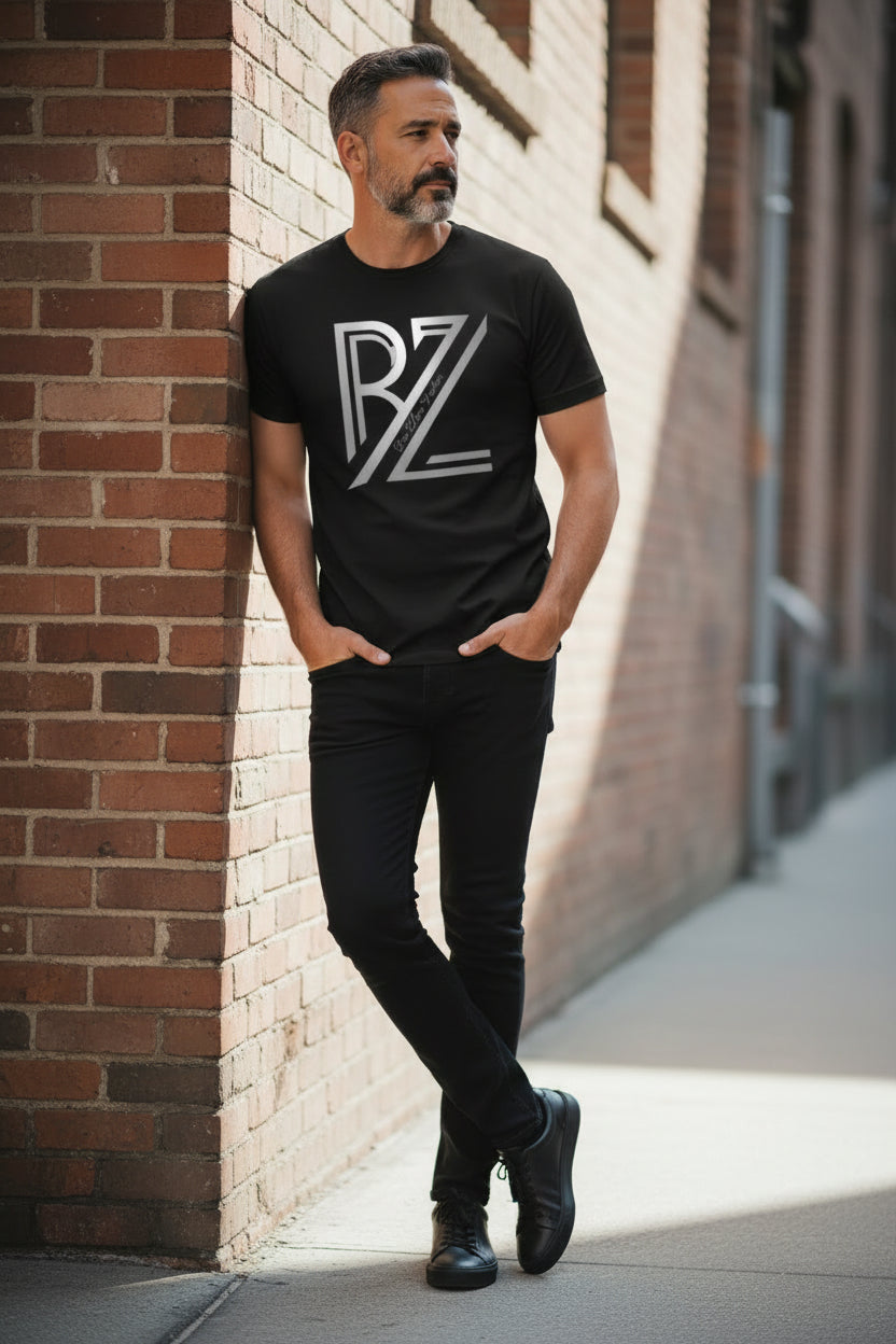 Man wearing a black t-shirt with a logo, standing against a brick wall.
