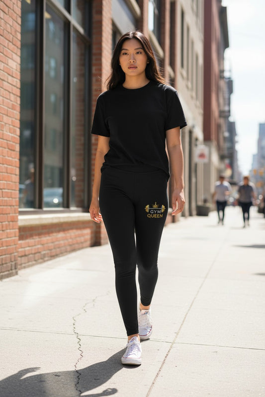Woman walking on a city street wearing black leggings with 'Queen' printed on them.